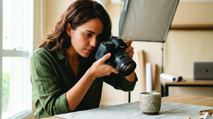 Fotógrafo profissional fotografando produto com cuidado técnico em estúdio bem iluminado